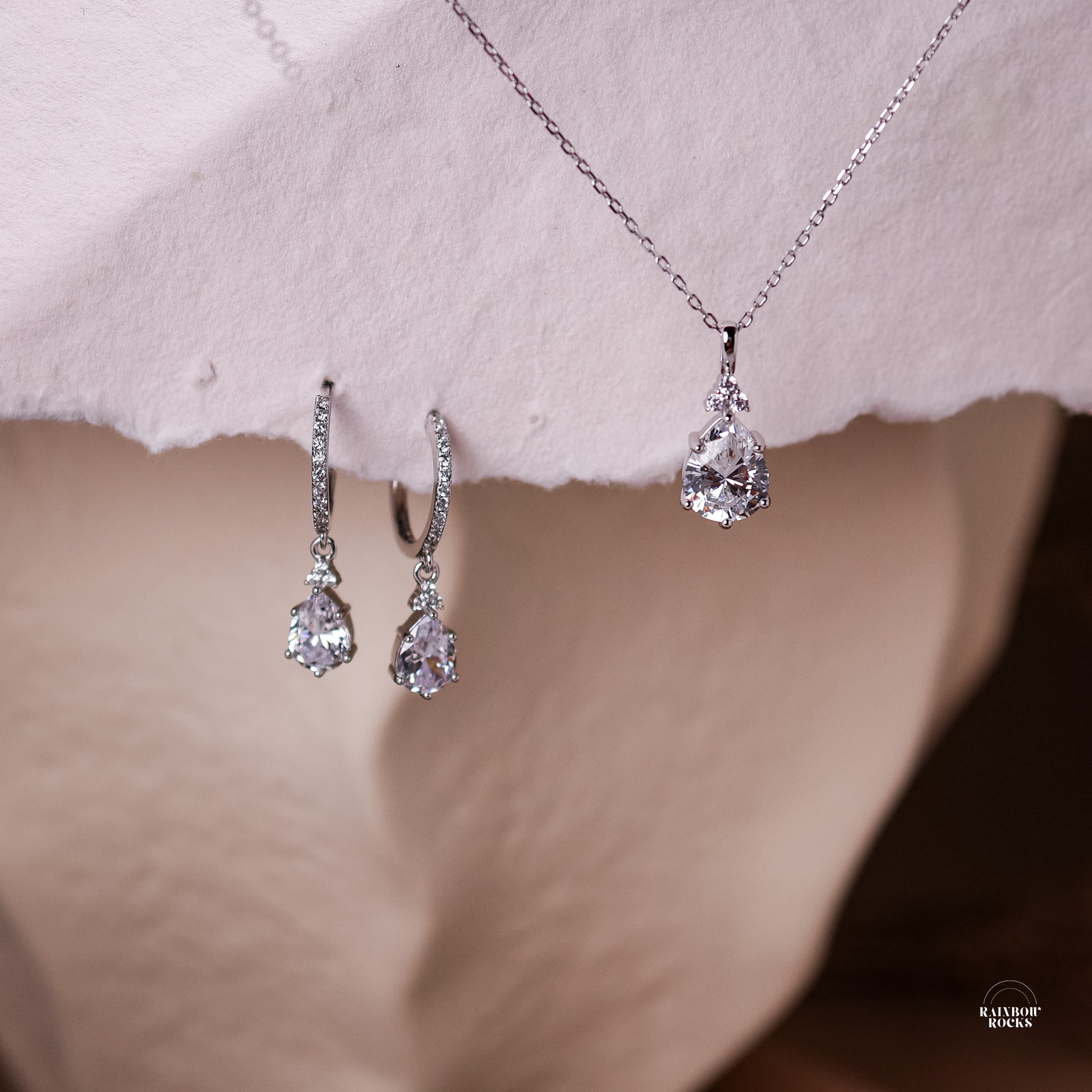 Diamond Cz Hoop Earrings sterling silver displayed with matching necklace hanging from cotton paper
