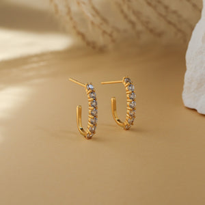Pair of Carina CZ J-hoop earrings standing on a beige background - Rainbow Rocks