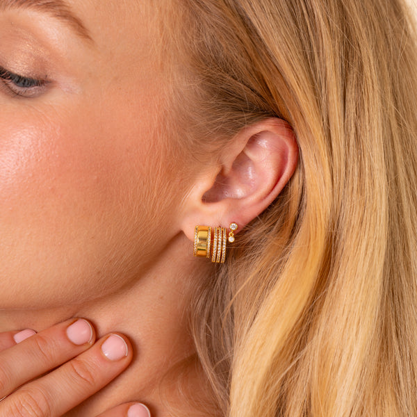 Model wearing the Vega triple-row pave hoop styled with other gold CZ earrings in an ear stack - Rainbow Rocks
