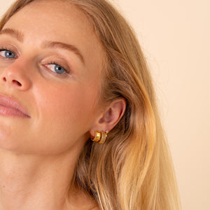 Close up of an ear styled with the Vega triple-row CZ hoop and gold stacking earrings - Rainbow Rocks