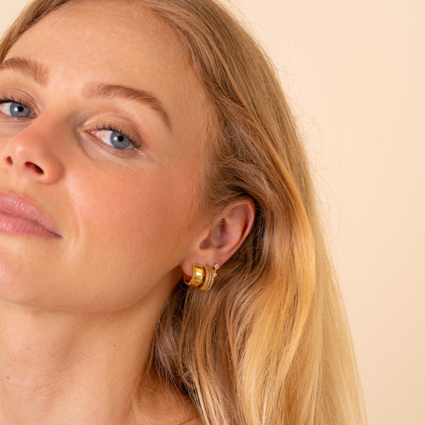 Close up of an ear styled with the Vega triple-row CZ hoop and gold stacking earrings - Rainbow Rocks