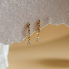 Lyra gold curved drop earrings with graduated white CZ and a pear-cut drop - Rainbow Rocks