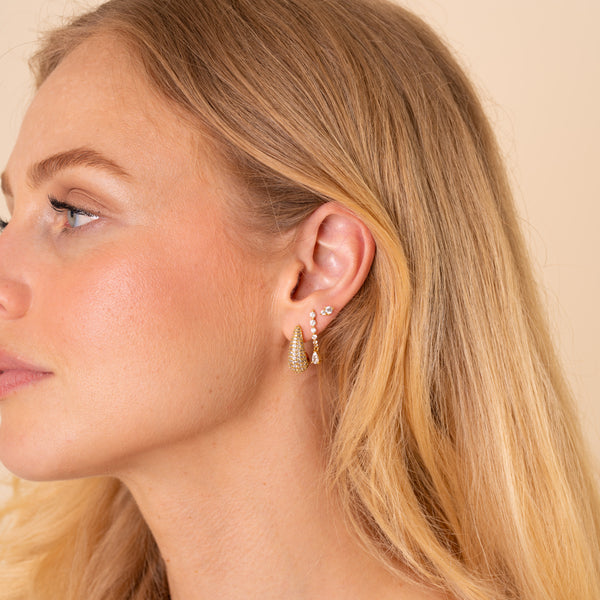 Model wearing an ear stack of the Adara pave teardrop hoop, Lyra curved drop and Stella two-stone stud, 18K gold plated - Rainbow Rocks